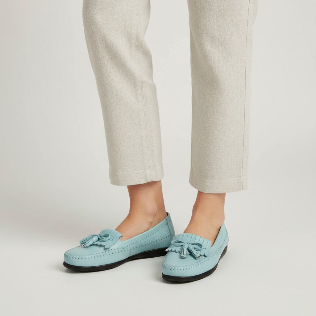 Light blue loafers worn with beige pants on a plain background