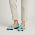 Light blue loafers worn with beige pants on a plain background