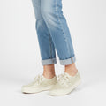 White sneakers worn with light blue jeans on a white background