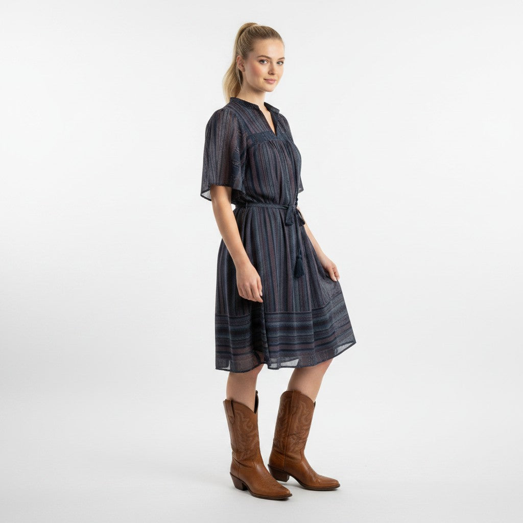 Woman wearing a dark striped dress and brown boots on a white background