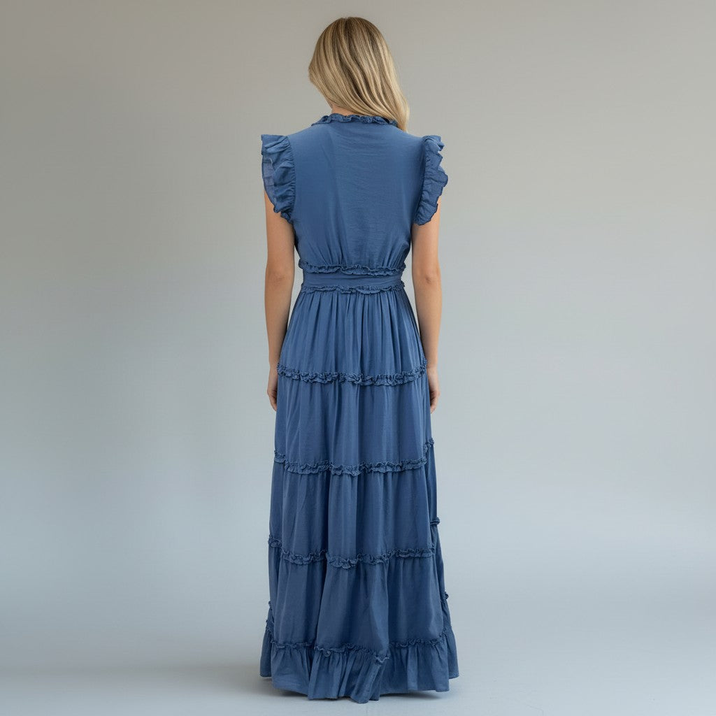 Woman wearing a blue dress with ruffled sleeves and bottom on a plain background
