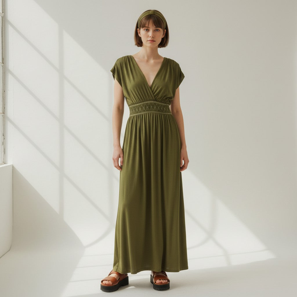 Woman wearing a green dress standing in a softly lit room.