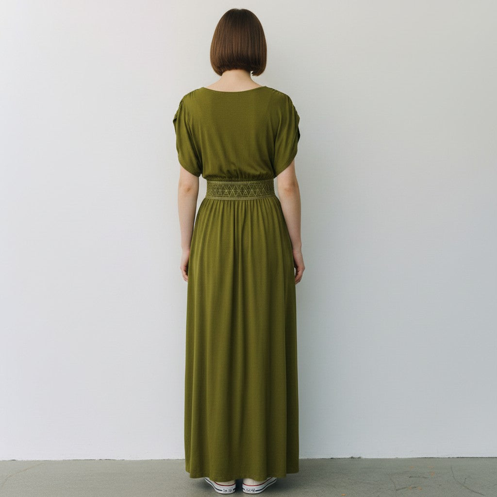 Person wearing a long green dress against a plain white background