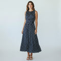 Woman wearing a navy polka dot dress on a white background