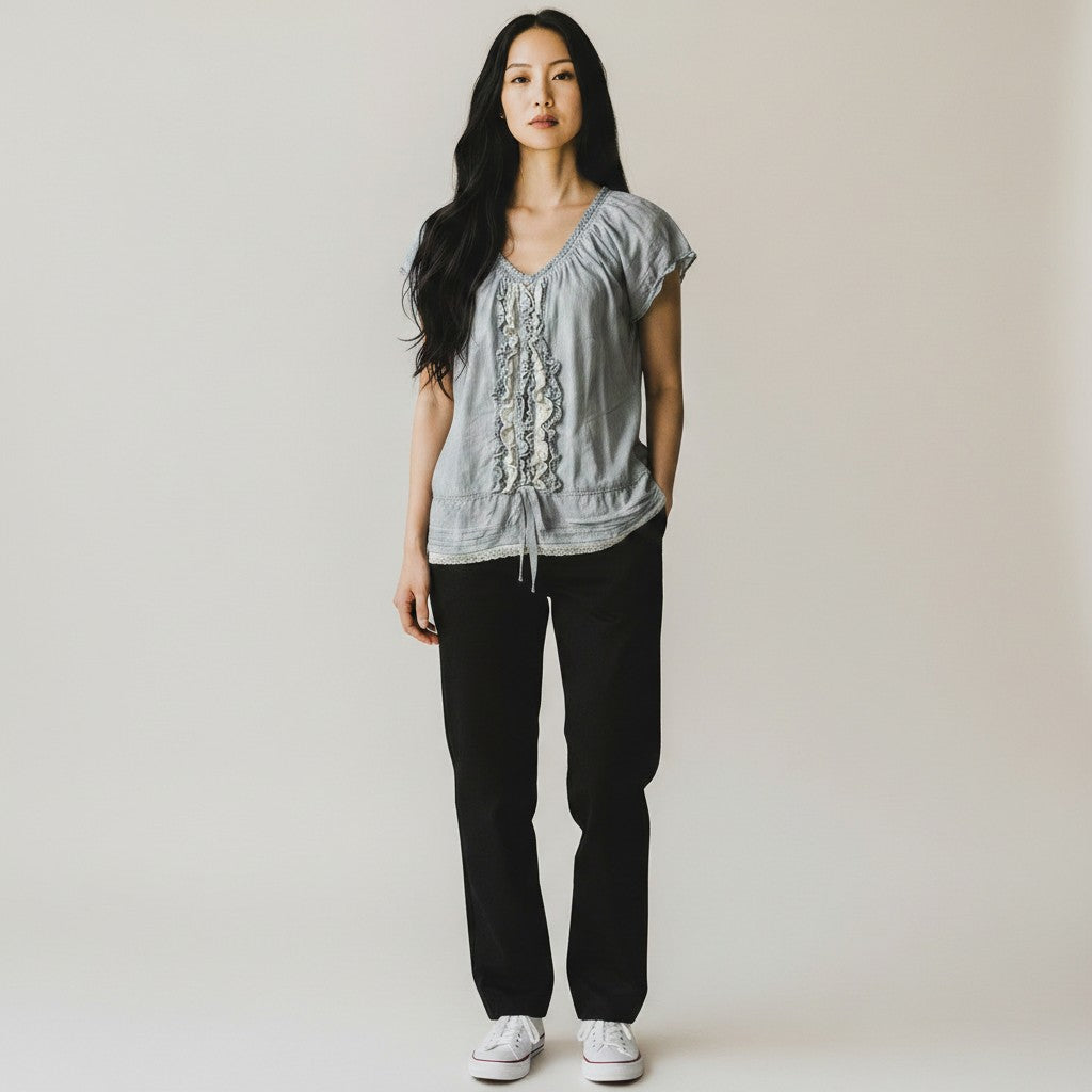 Woman wearing a gray top and black pants against a plain background