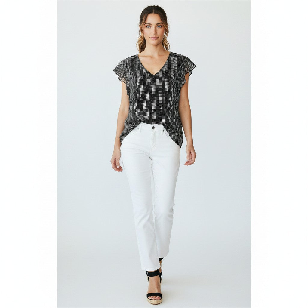 Woman wearing a dark patterned top and white pants on a white background
