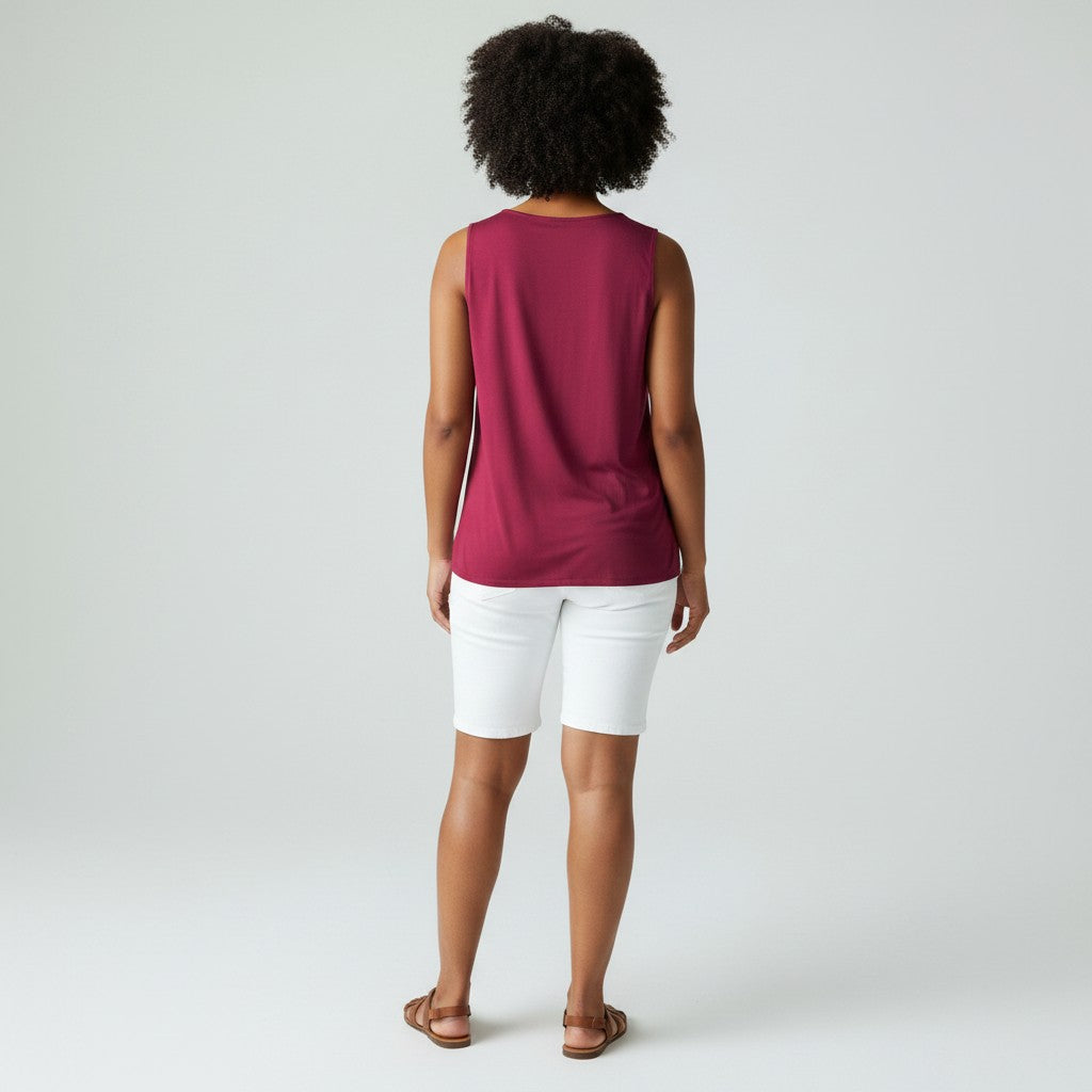 Person wearing a sleeveless burgundy top and white shorts on a plain background