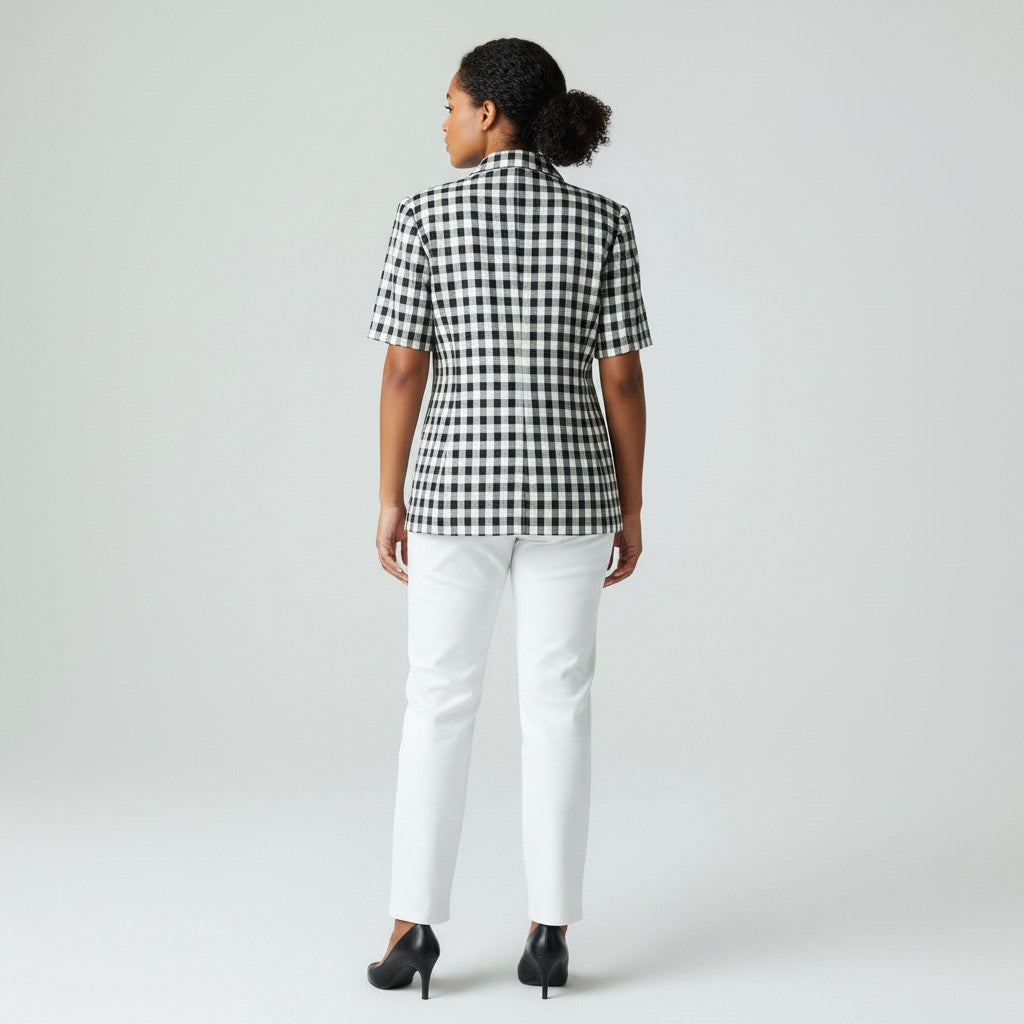 Woman wearing a black and white checkered shirt and white pants on a plain background