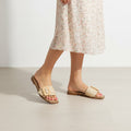 Beige sandals worn with a floral dress on a light background