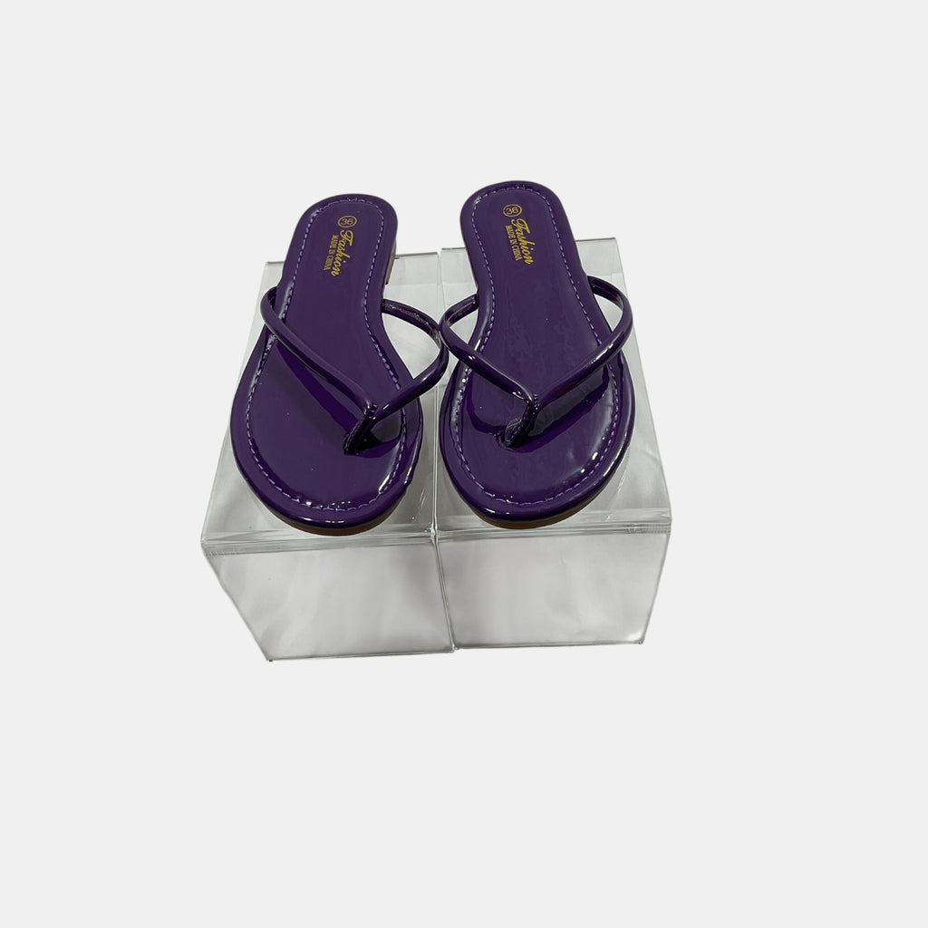 Purple flip-flops in a clear plastic box on a white background