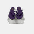 Purple flip-flops in a clear plastic box on a white background