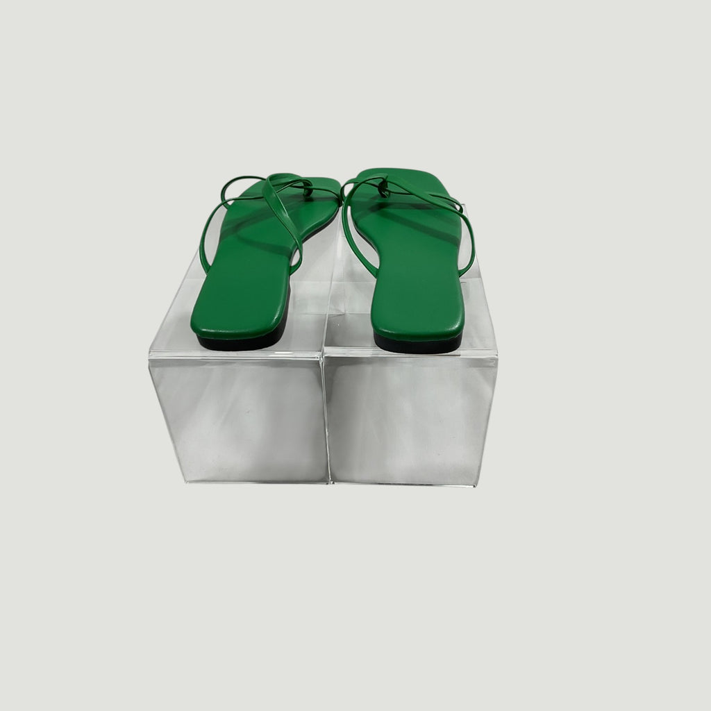 Green sandals on a transparent stand against a light gray background