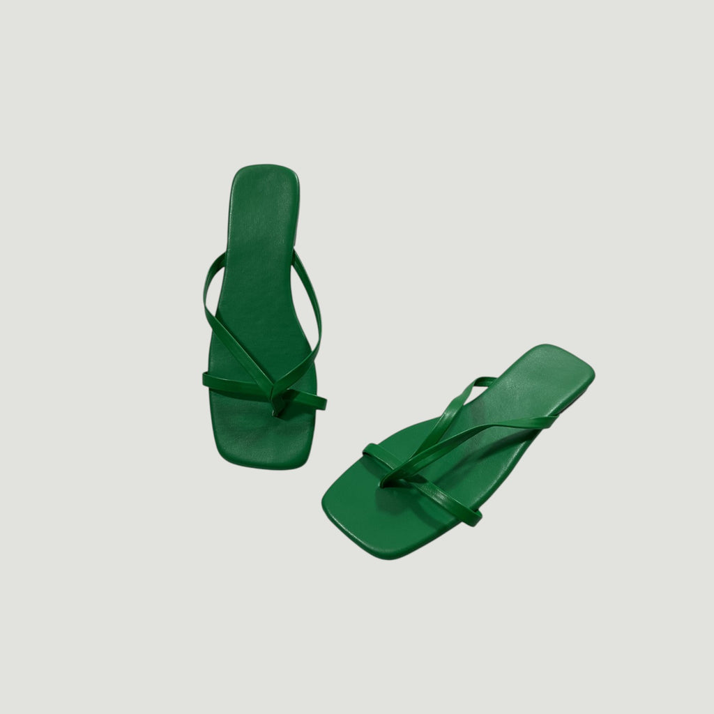Pair of green flip-flops on a light gray background