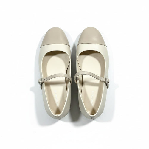 Pair of beige flat shoes with a strap on a white background