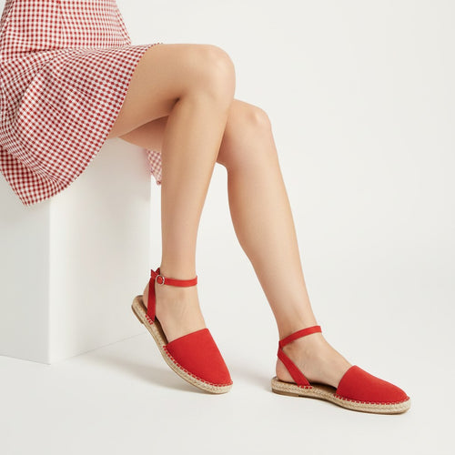 Red sandals worn with a checkered dress on a white background