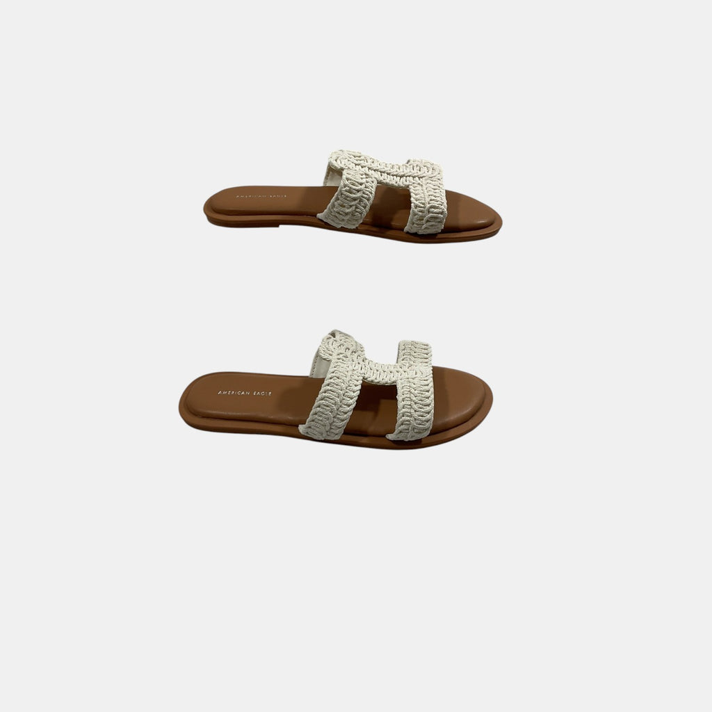 Pair of sandals with white woven straps on a light gray background