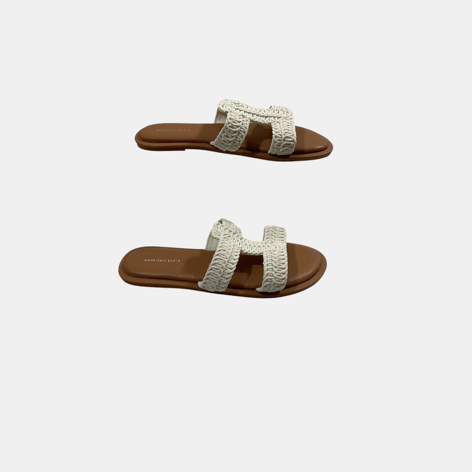 Pair of sandals with white woven straps on a light gray background