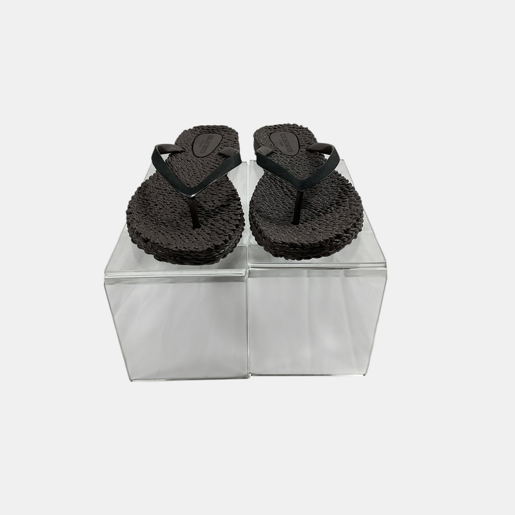 Pair of black flip-flops on a transparent stand against a white background