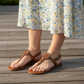 Brown sandals worn with a floral dress on a wooden floor