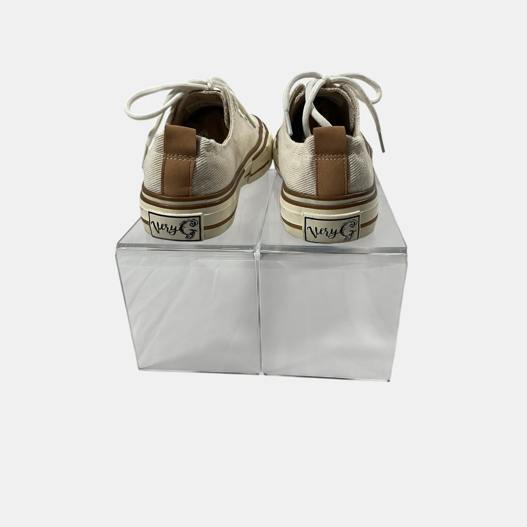 Pair of beige sneakers with brown soles on clear stands against a white background