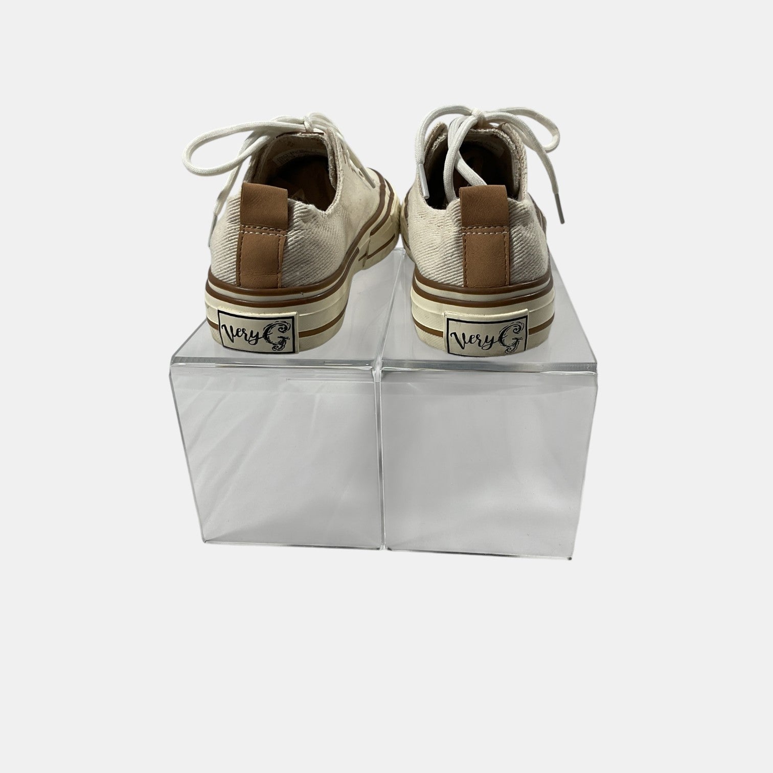 Pair of beige sneakers with brown soles on clear stands against a white background