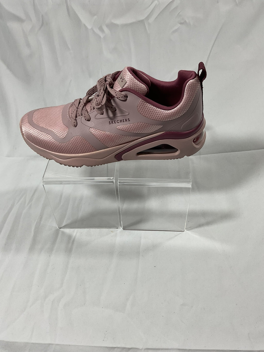 Pink sneaker on a clear stand against a white background