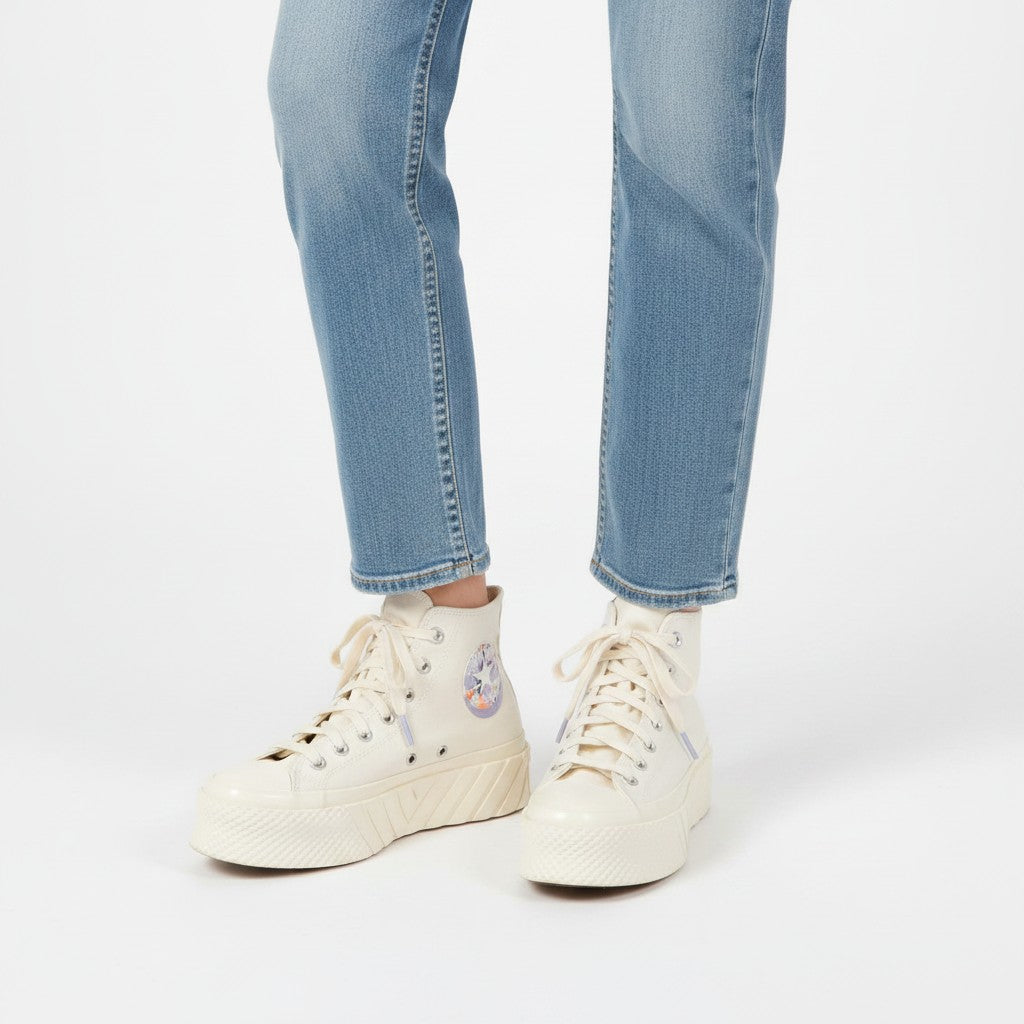 White high-top sneakers worn with light blue jeans on a white background