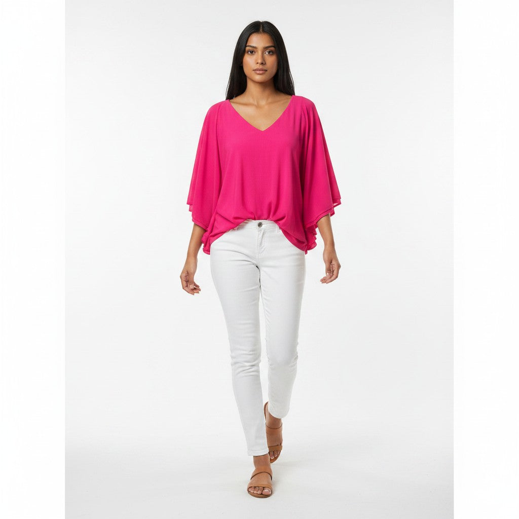 Woman wearing a bright pink top and white pants on a white background