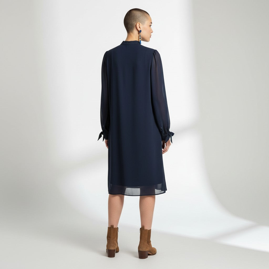 Person wearing a navy blue dress with long sleeves on a white background