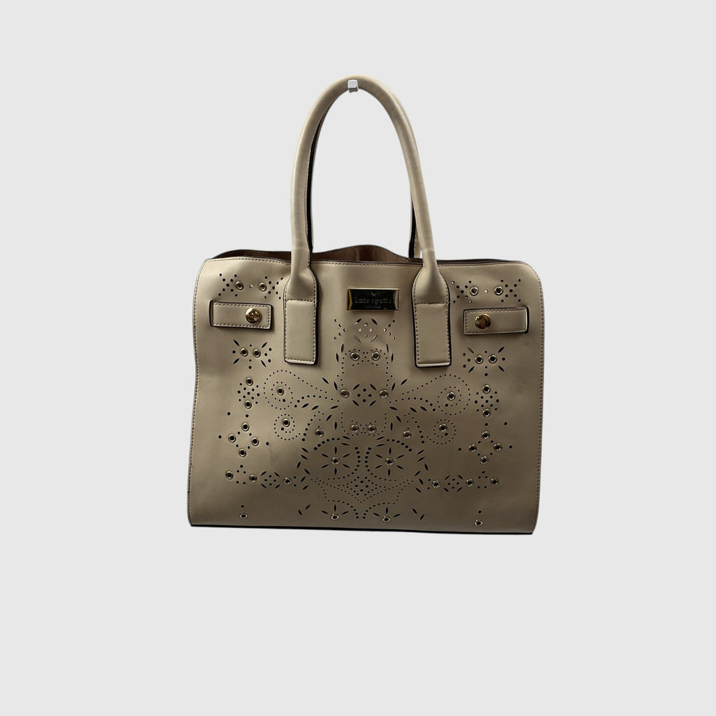 A structured taupe leather handbag with laser-cut floral patterns, dual top handles, and gold-tone hardware, shown against a light gray background.