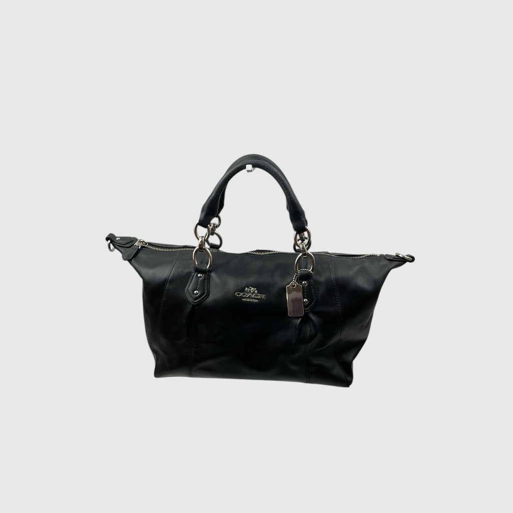 A black leather Coach handbag with dual top handles, a front zip closure, and a hanging metal key tag, shown against a light gray background.