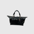 A black leather Coach handbag with dual top handles, a front zip closure, and a hanging metal key tag, shown against a light gray background.