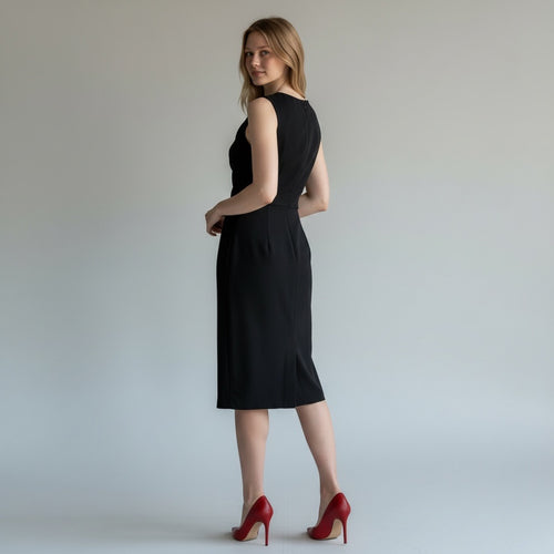 Woman wearing a black dress with red high heels on a plain background
