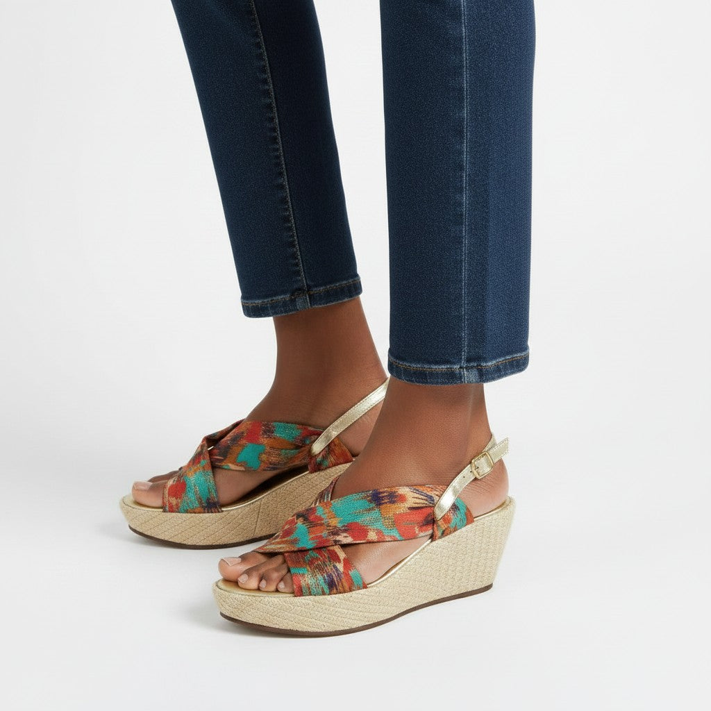 Colorful wedge sandals worn with blue jeans on a white background