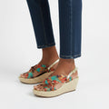 Colorful wedge sandals worn with blue jeans on a white background