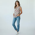 Woman wearing a floral sleeveless top and blue jeans on a white background