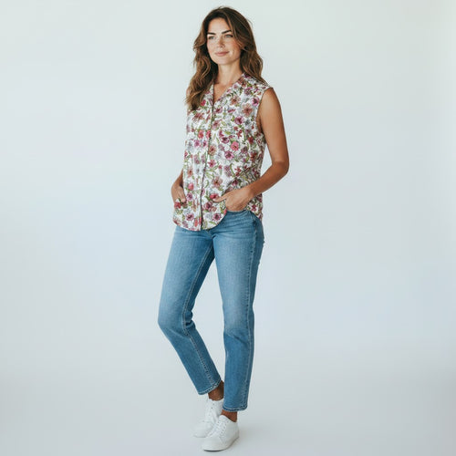 Woman wearing a floral sleeveless top and blue jeans on a white background