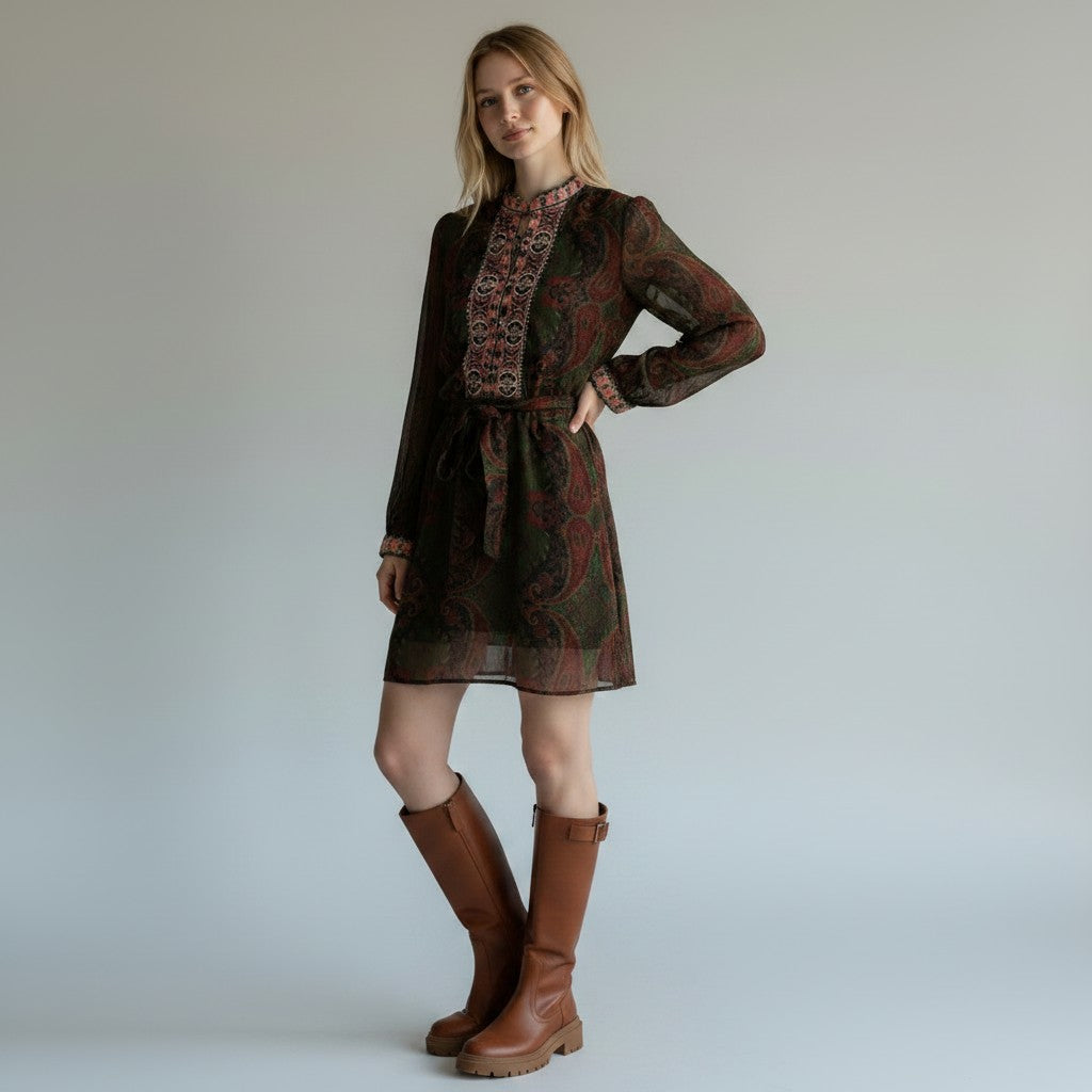 Woman wearing a patterned dress and brown boots against a plain background