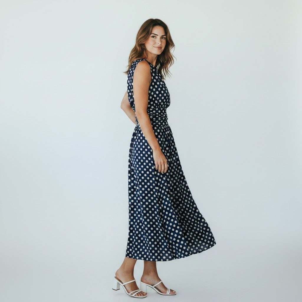 Woman wearing a navy polka dot dress on a white background