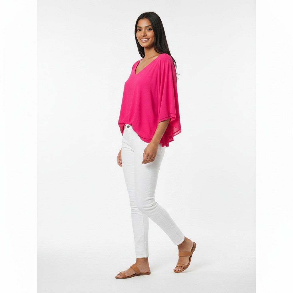 Woman wearing a bright pink top and white pants on a white background