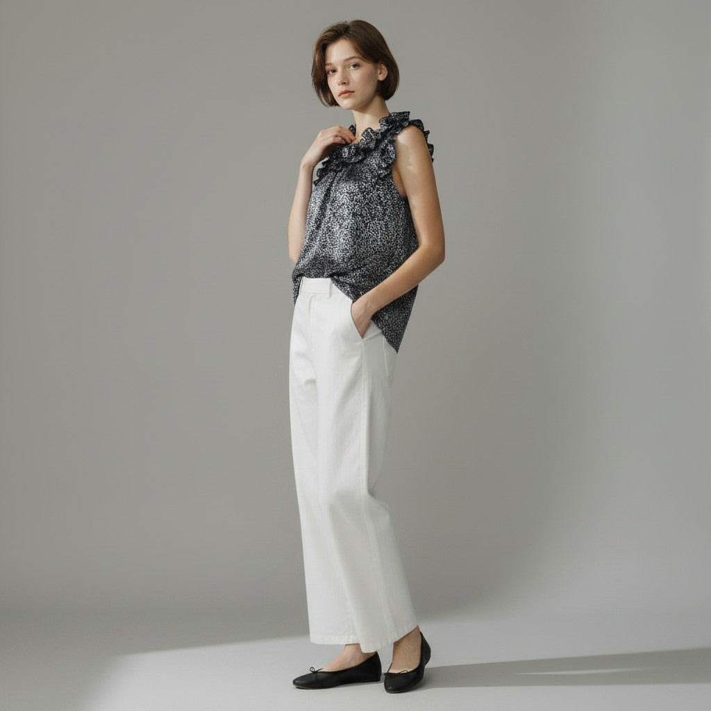 Woman wearing a navy floral top and white pants on a gray background