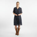 Woman wearing a dark striped dress with brown boots on a white background