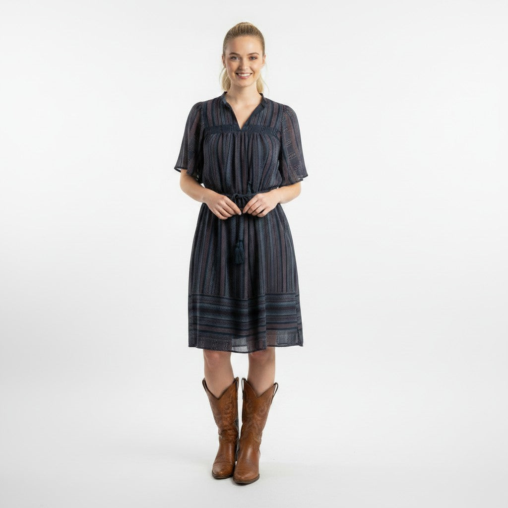 Woman wearing a dark striped dress with brown boots on a white background