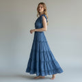 Woman wearing a blue tiered dress against a plain background